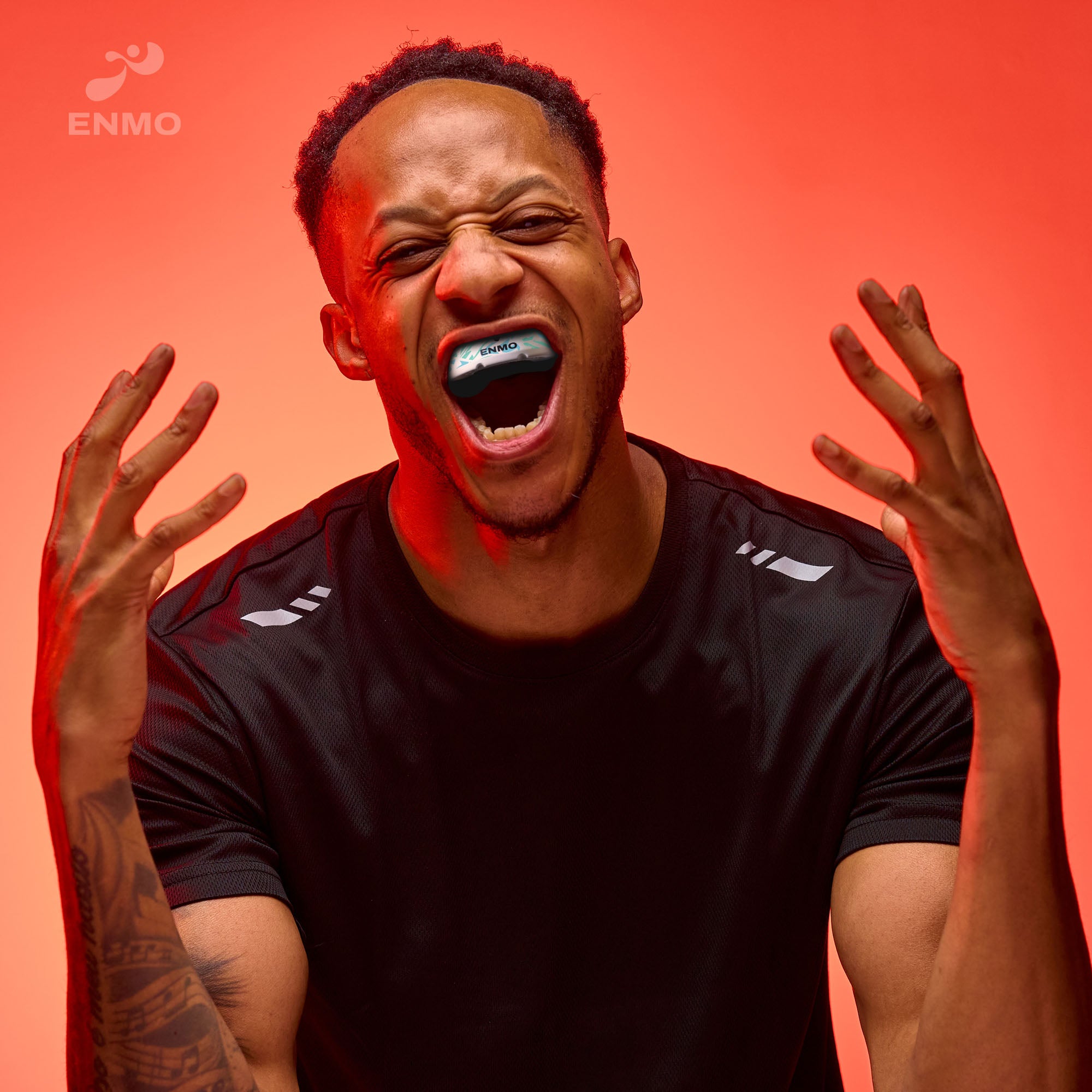 Man wearing Enmo mouthguard with a red background and Enmo branding.