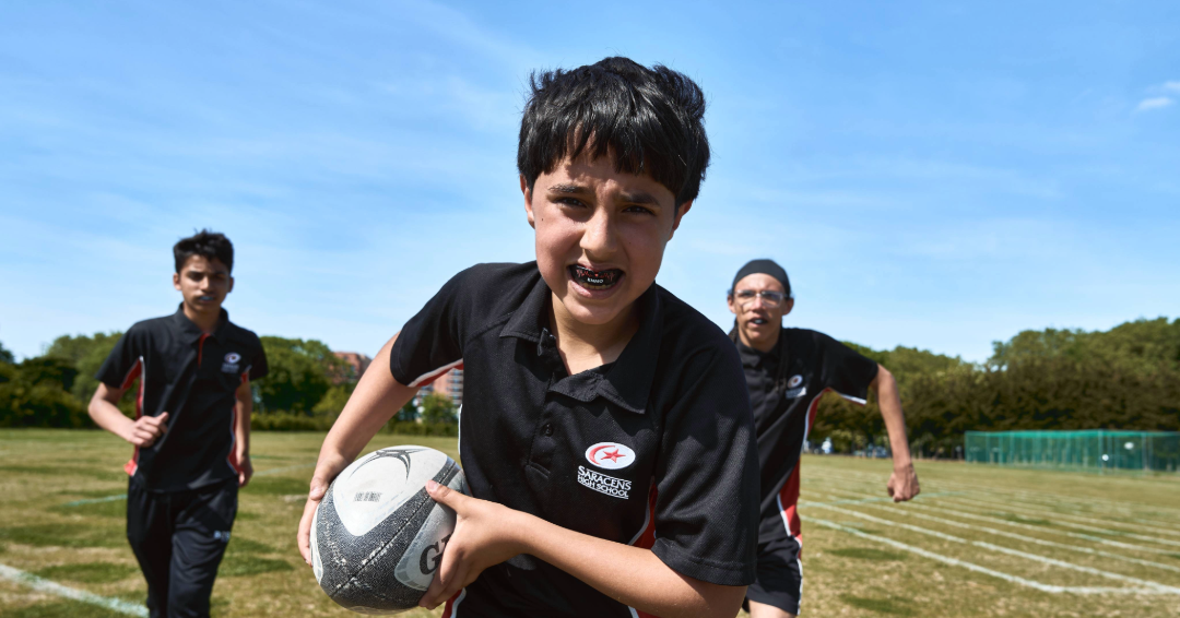 Young rugby player from Saracens school tackling with confidence, wearing protective mouthguard for safety