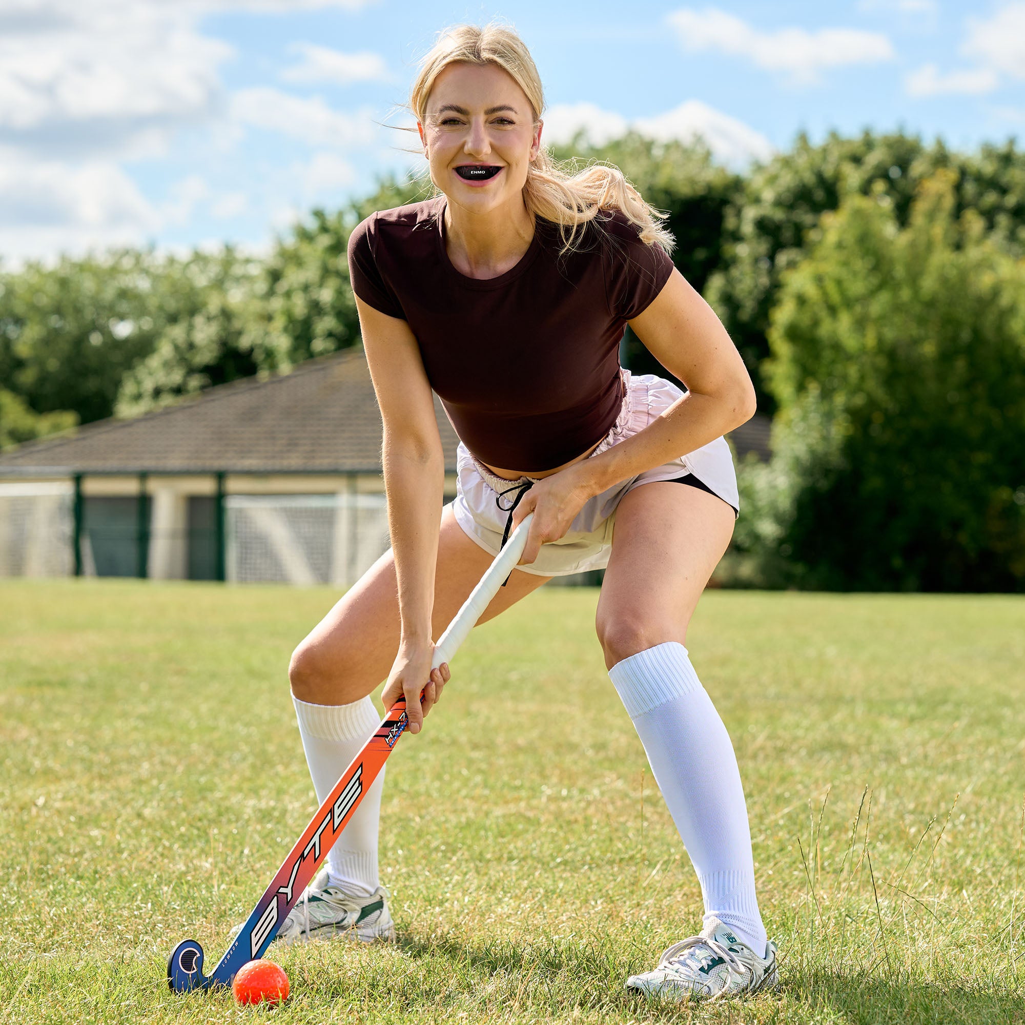 Female hockey player wearing an enmo red and black mouthguard.